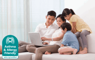 Smiling family of four using a laptop together in a bright living room, with the Asthma & Allergy Friendly® Certification mark in the corner on Amazon Prime Day 2025