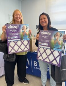 Community members holding Kleenex® Elite Allergen MERV 13 Certified air filters at a donation event.