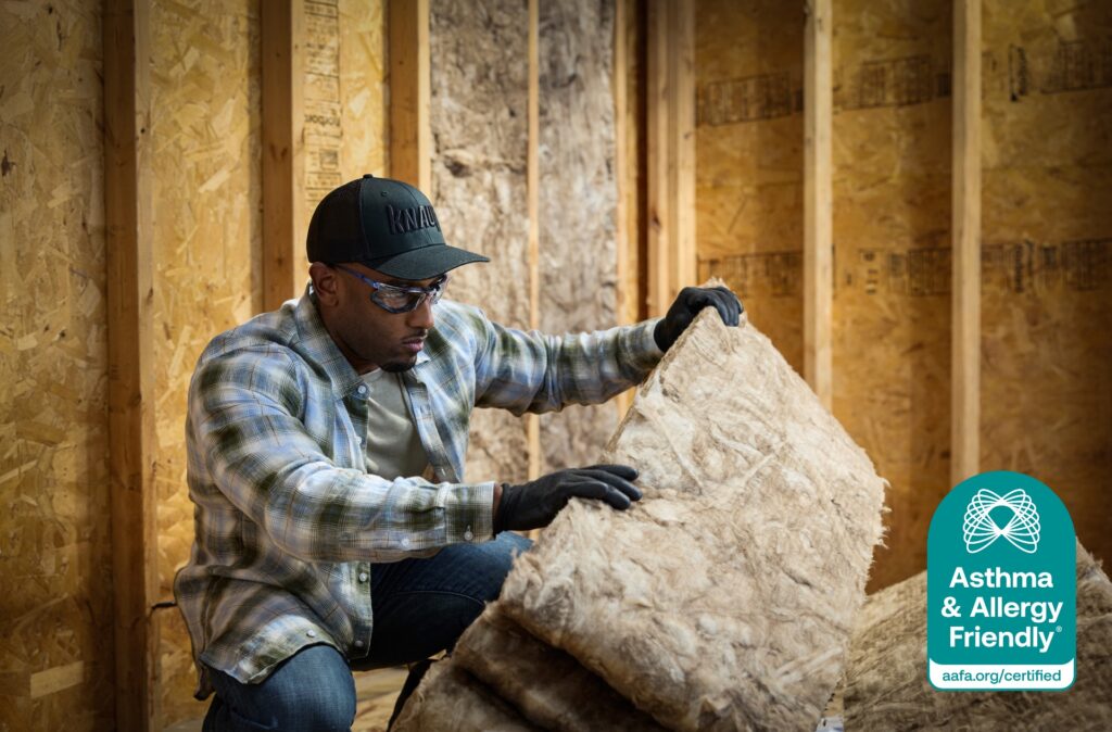 Builder handling Knauf Performance+® fiberglass insulation, Certified Asthma & Allergy Friendly® for low VOC emissions.