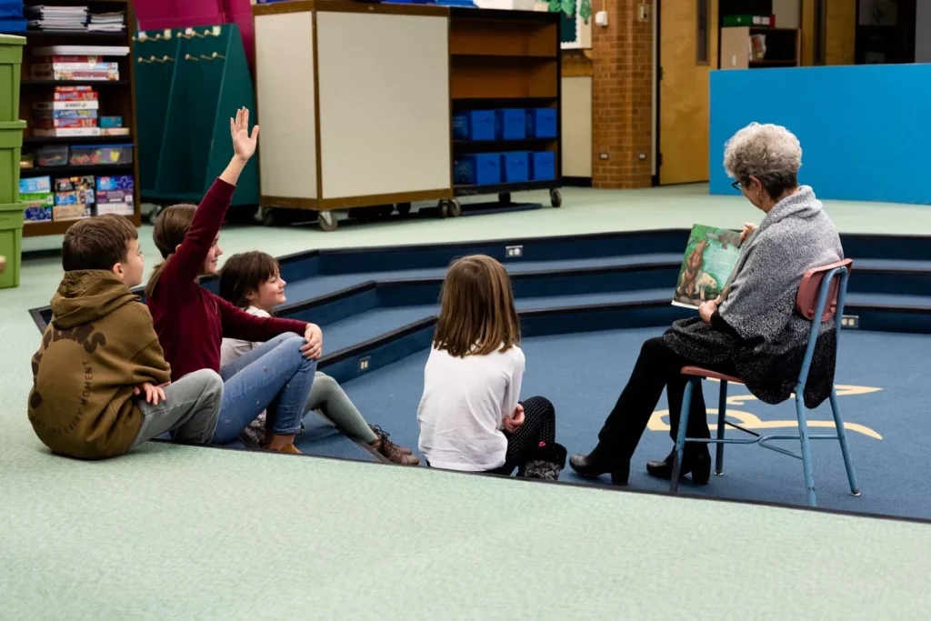 Primary school classroom with teacher reading to students seated on flooring designed to support a clean, comfortable indoor environment